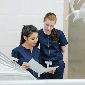 Zwei Pflegerinnen sehen sich eine Patientenakte im Behandlungsraum an